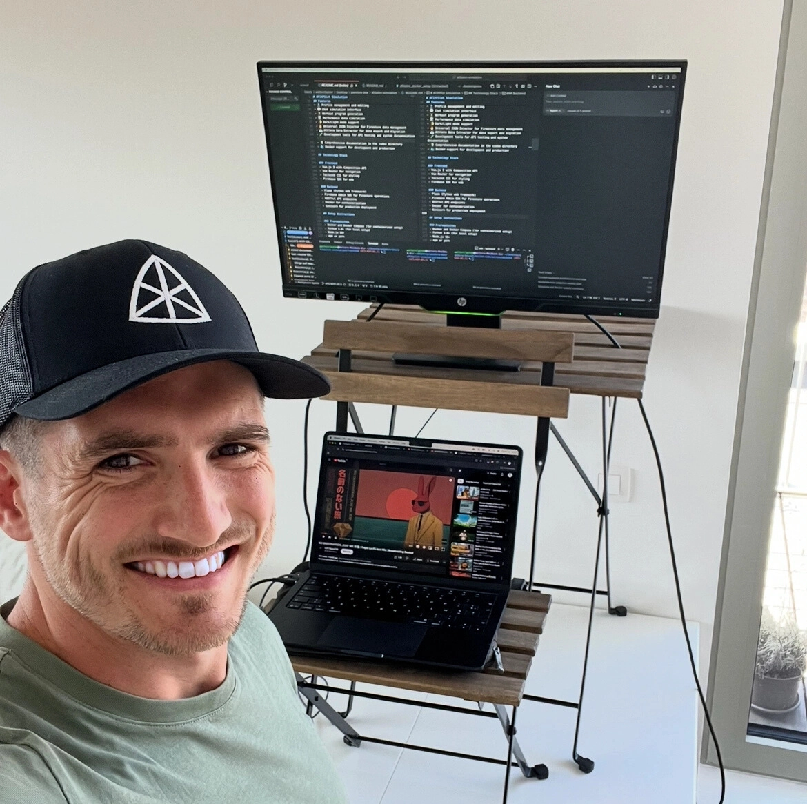Founder of Afitpilot working at a standing desk with a laptop and external monitor displaying code, combining sports science and software development.